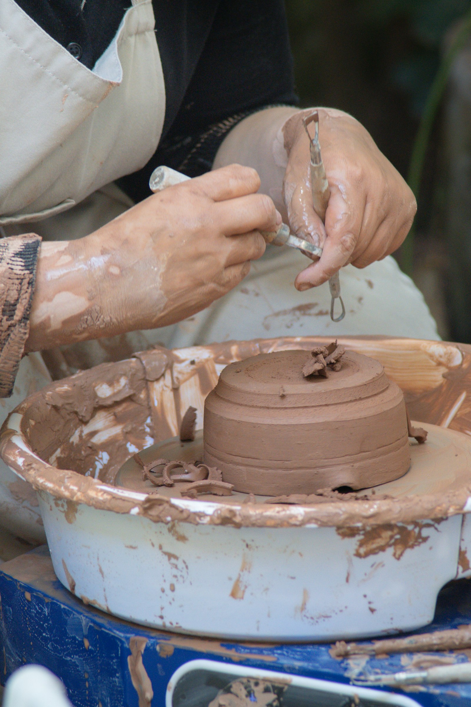 Hands shaping clay on a pottery wheel