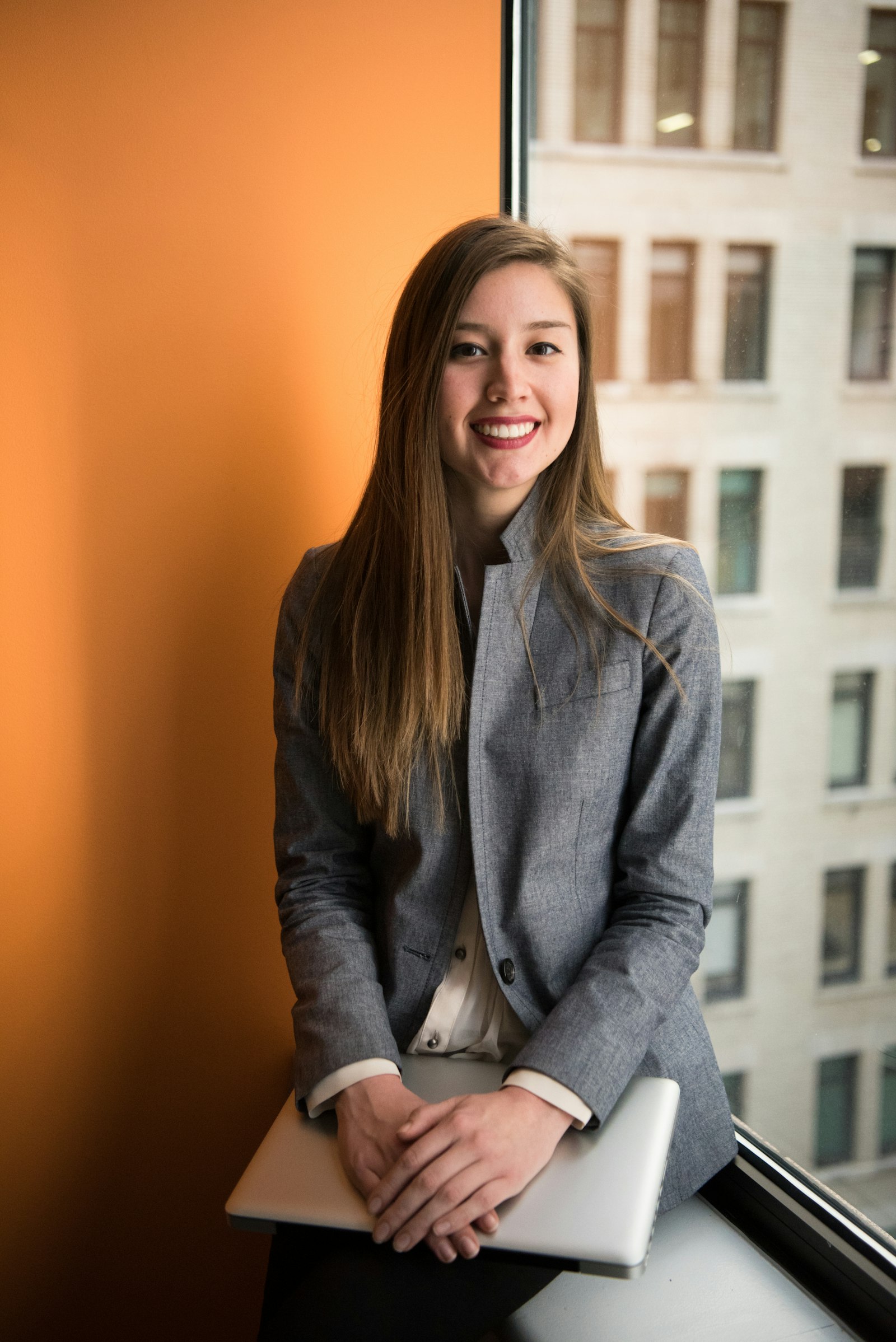 Businesswoman in gray blazer against orange wall